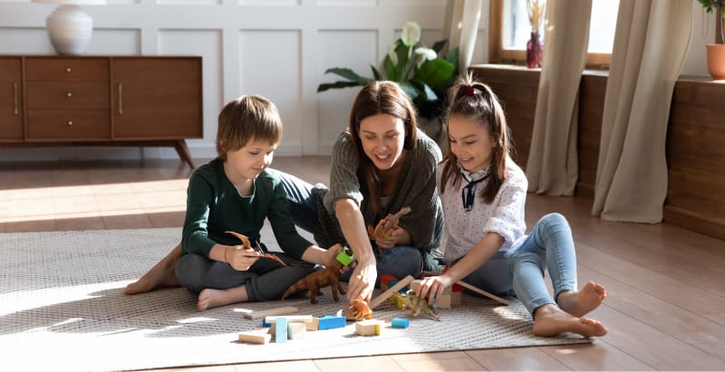 Une mere et ses deux enfants jouant dans le salon.